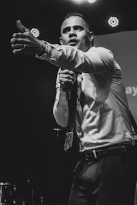 Black and white photo of a passionate speaker addressing an audience with a microphone on stage.