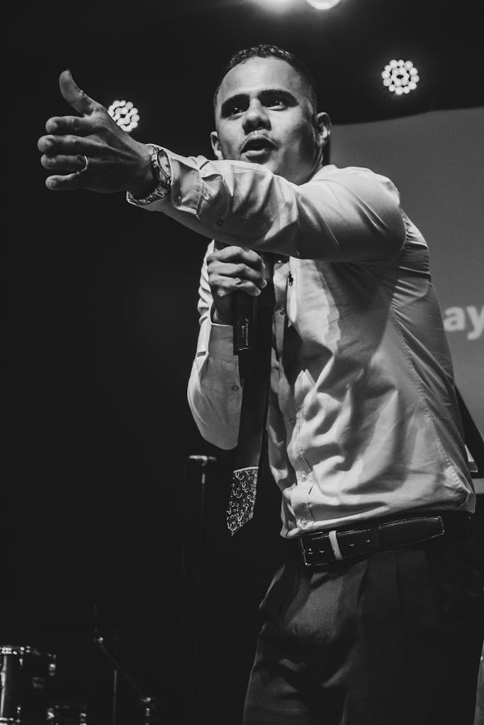 Black and white photo of a passionate speaker addressing an audience with a microphone on stage.