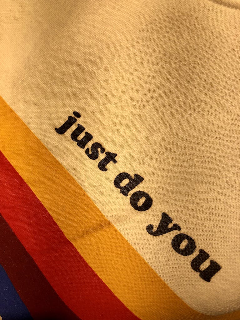 Close-up of vibrant fabric with motivational text 'just do you' on colorful stripes.