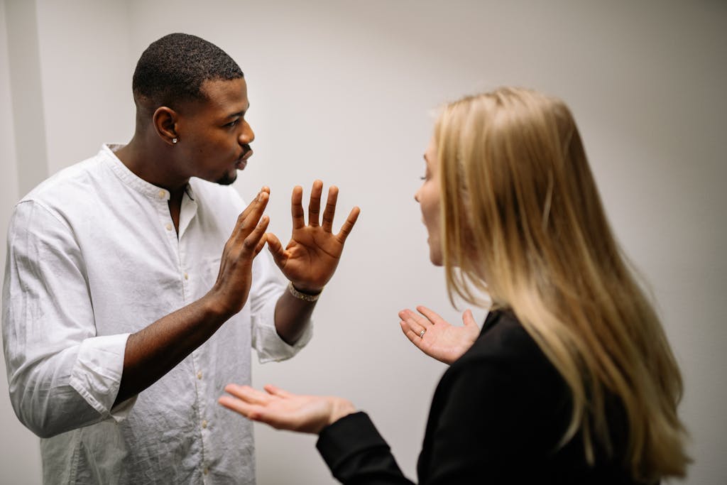 Frustrated coworkers in heated discussion, expressing disagreement in office setting.