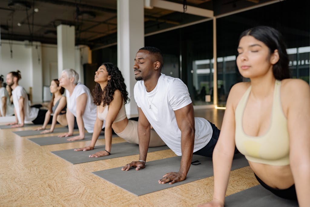 Photo by Yan Krukau A diverse group of adults practicing yoga poses in a light-filled studio.