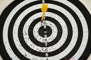 Close-up of a dart hitting the bullseye on a black and white target board symbolizing success.