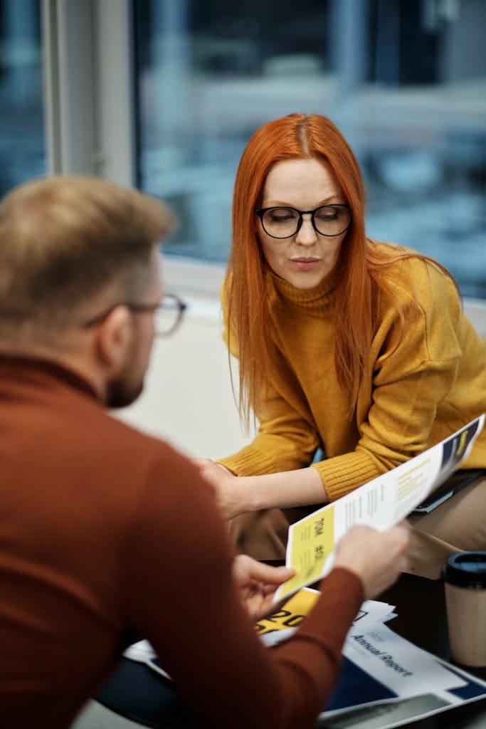 Photo by Jack Sparrow Two colleagues engaged in a discussion during an office meeting, reviewing documents.
